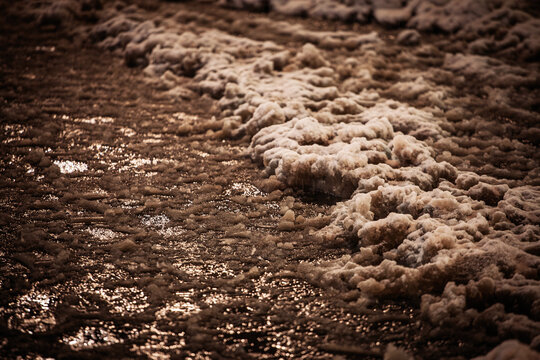 A muddy pedestrian path is covered with melting snow, wet slush and puddles at night. Reflections on the uneven surface show difficult winter walking conditions following snow and thawing weather.