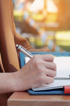 Vertical Close up women hands using pen planning. Female hand holding pen note Personal Organizer diary. Vertical Horizon Woman hands writing empty notebook planing meeting agenda on wooden table