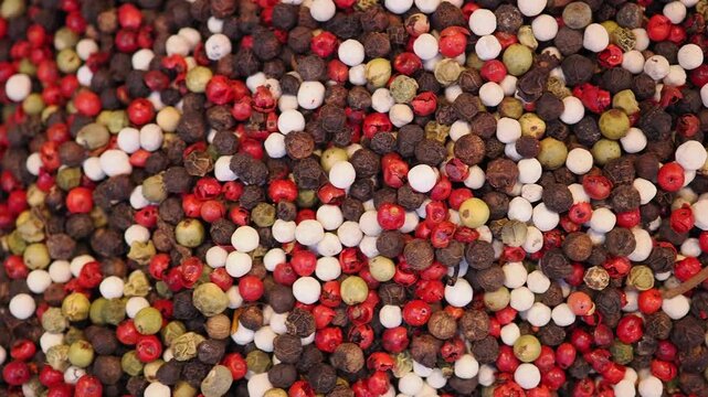 Mixed peppercorns spread across a surface for cooking