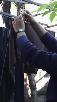 Person hanging brown clothing item on outdoor clothesline