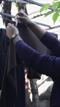 Slow motion person hanging brown clothing item on outdoor clothesline