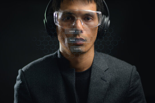 Young professional man wearing headset with holographic login interface in dark environment