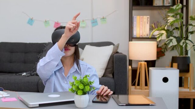 Asian Woman Interacting with Virtual Reality Headset at Home Desk