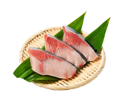 Three raw yellowtail fish fillets on a bamboo sieve with green leaf isolated on transparent background