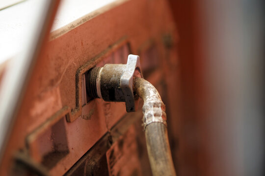 close-up of a dusty hose connection attached to the back of an old home appliance.