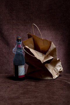 A bottle of champagne next to a crumpled bag on a brown background