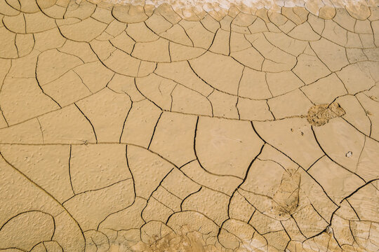 Parched Barren Clay Soil Ground Covered in Deep Sun-Baked Cracks, Fissures and Human Footprint