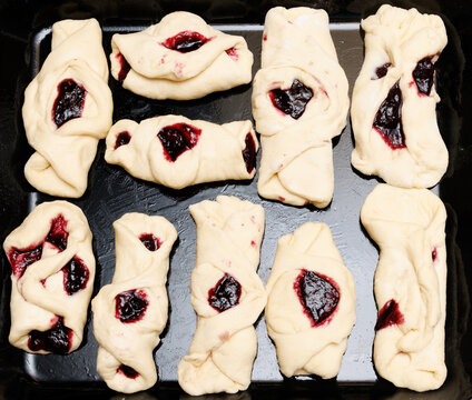 Unbaked rolls with dark berry filling on baking tray