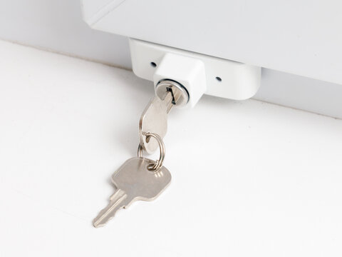 White lock with key attached to a white surface