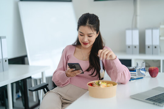 Asian woman in casual eating food during work in office