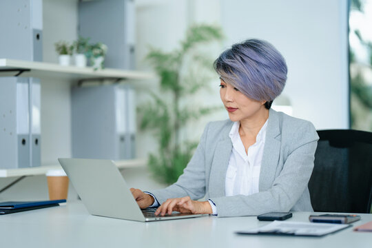 Asian senior businesswoman typing on laptop in office room