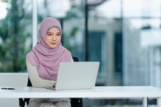 Women wearing hijab working on laptop in office