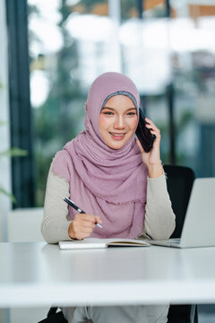 Women wearing hijab talking work on phone in office