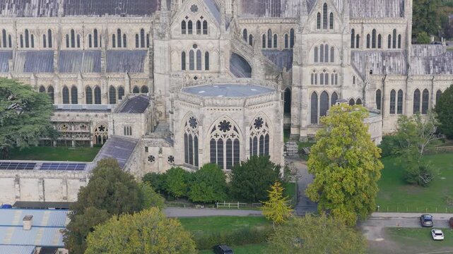 Aerial drone footage of the south transept and historic Gothic architecture of Salisbury Cathedral in Wiltshire, England. The view reveals detailed medieval stonework, pointed arch windows