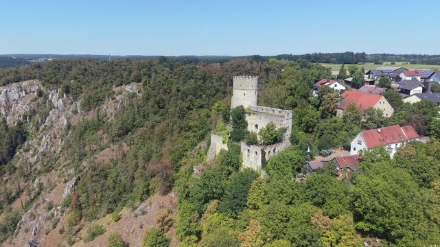 Aerial approach toward Burg Randeck, a ruined medieval castle perched on a forested limestone crag above Essing in the Altmuhl Valley, Bavaria.