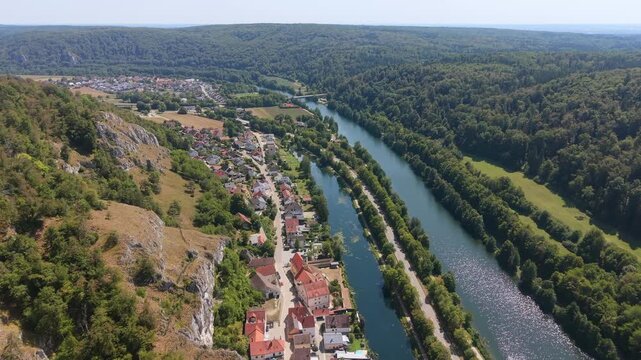 Aerial footage of the small village of Essing stretched along the Altmuhl River below steep wooded slopes in the Altmuhl Valley, Bavaria, Germany.