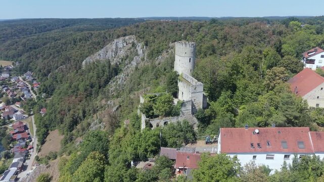 Drone shot of the medieval Burg Randeck keep and ruined walls rising above white limestone cliffs, with the village of Essing below, Bavaria, Germany.