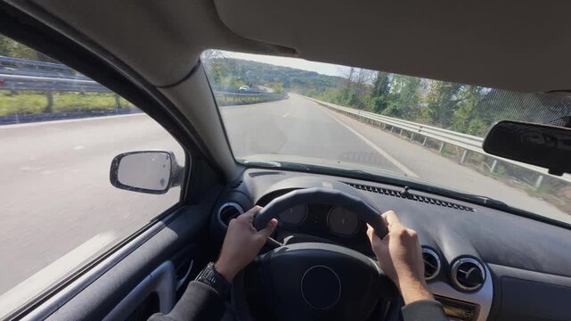 Driving car POV interior view of hands on steering wheel along highway