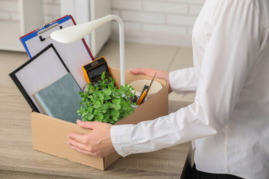 Unemployment and job loss, employee packing personal belongings in cardboard box after being fired or resigning from corporate office job