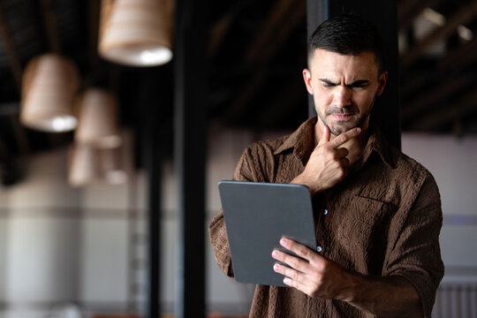 Worried man looking at financial problems and stock market losses on a digital tablet