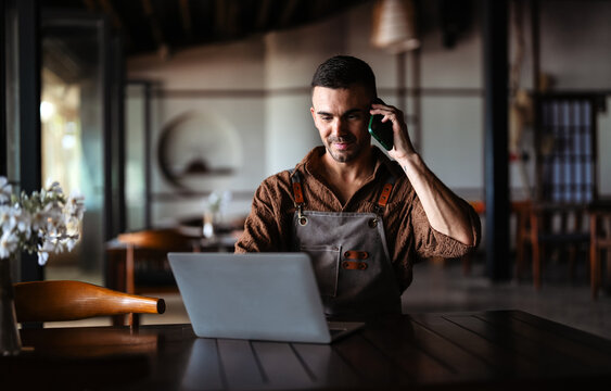 Successful male entrepreneur managing restaurant operations on a laptop