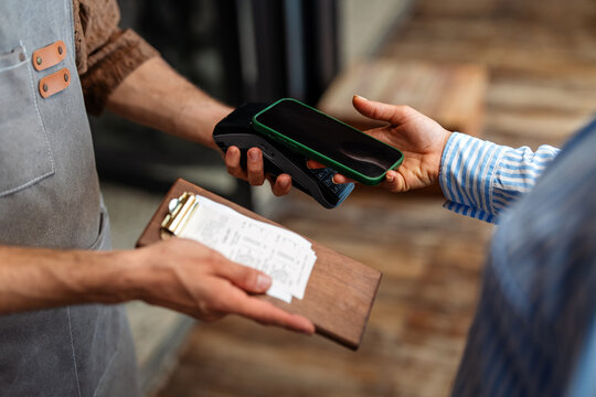 Modern hospitality, a smiling waiter accepts contactless payment from a happy customer,