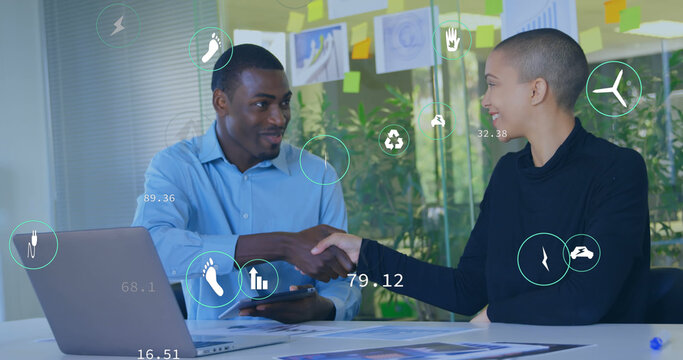 Image of icon in circles over diverse coworkers shaking hands in office