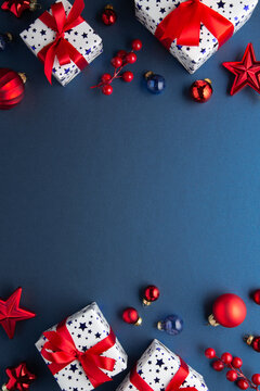 Blue Christmas and Happy New Year holiday background with gift boxes, red ribbon bows and festive red ornaments, flat lay with copy space. Greeting card.