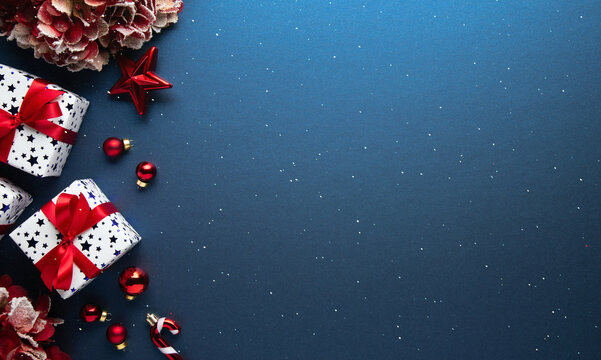 Blue Christmas and Happy New Year holiday background with gift boxes, red ribbon bows and festive red ornaments, flat lay with copy space. Greeting card.