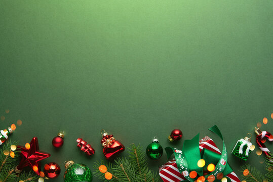 Merry Christmas and Happy Holidays greeting card, frame, banner. New Year. Red Christmas ornaments and gifts, presents on green background top view. Xmas holiday festive theme. Christmas decoration