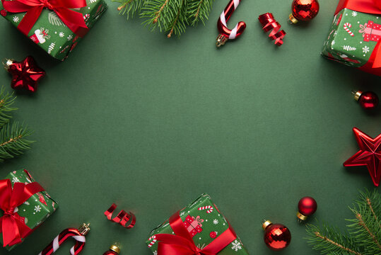 Green Christmas and Happy New Year holiday background with gift boxes, red ribbon bows and festive red ornaments, flat lay with copy space. Greeting card.