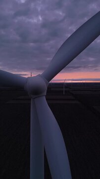 Aerial View of Wind Turbine Blades at Sunset Over Wind Farm, Vertical