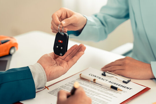 Customer giving stack of dollar banknotes to agent and receiving car key for auto loan or purchase contract