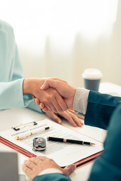 Car dealer and customer shaking hands after signing auto loan lease contract agreement at office