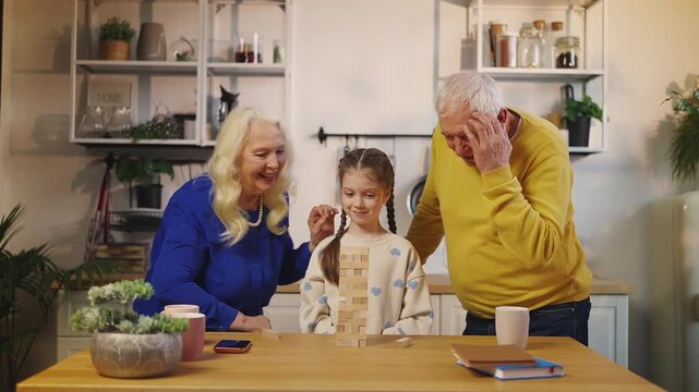 Happy grandparents and grandchild play leaning tower game together at home