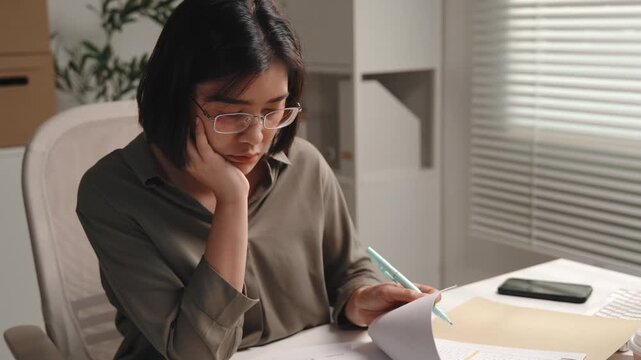 Accounting and finance, female accountant reading financial documents, reviewing paperwork and thinking at office desk, focused on audit, tax preparation, budget analysis and year end reporting.