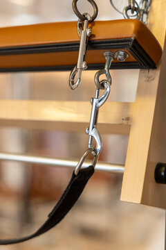 Pilates reformer clips and strap attached to a wooden exercise frame