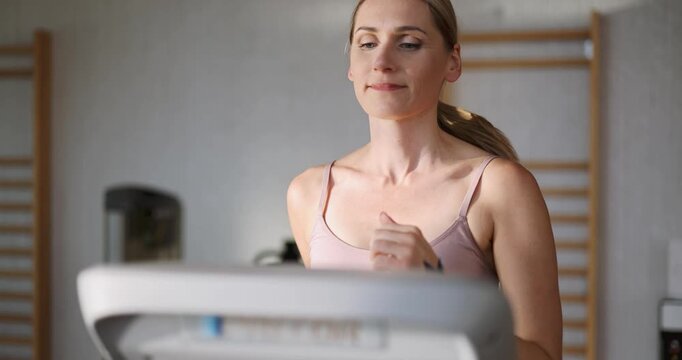Middle aged woman running on a treadmill at fitness center gym
