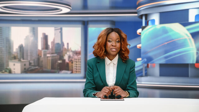 Portrait of  Black Female Journalist Presenting Daily News Headlines From the Studio Anchor Presenter Desk, Speaking Directly to Camera and Leading International Coverage During a Live Tv Broadcast.