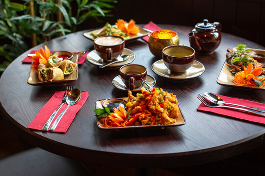 Thai dishes featuring spring rolls, fried food, salad, tea
