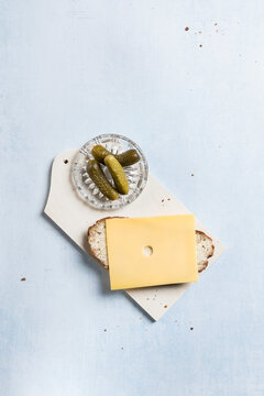 Cheese slice on Grey bread with pickles on a cutting board