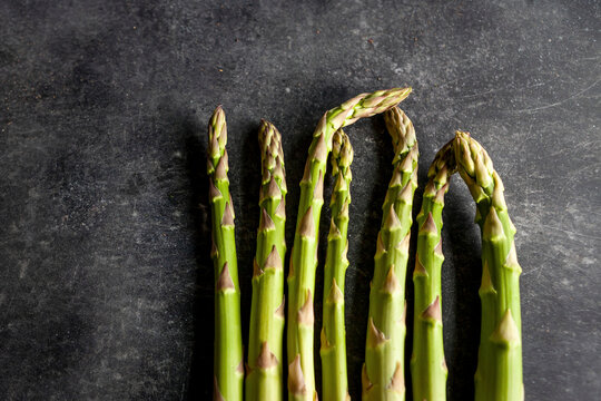 Fresh green asparagus stalks on dark surface