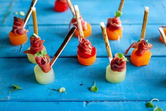 Melon skewers with Parma ham on blue wooden table