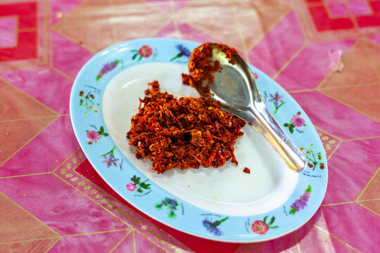 Thai red curry paste on a floral plate with metal spoon