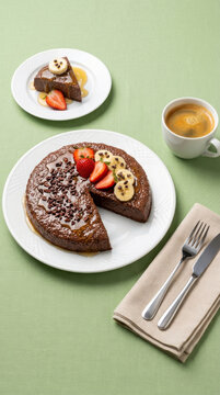 Healthy chia and cocoa pudding with strawberries, banana, honey drizzle, and a cup of espresso on a green table