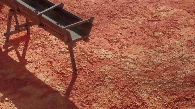 A wooden trough rests on the parched, cracked ground, surrounded by a vast expanse of dry earth. The sun shines brightly, highlighting the weathered texture of the wood.