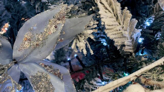 Elegant silver Christmas flower with sparkling sequins and glitter, blue fairy lights and snowy evergreen branches, festive winter holiday decoration with frosted details