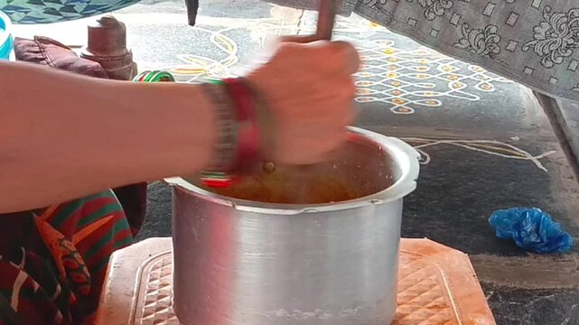 A woman's hands mixing dal in a metal pot inside a home kitchen cooking preparation meal food culinary