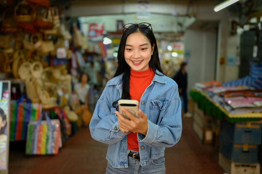 Young Asian Woman Using Smartphone for Navigation While Exploring Chinatown Market at Night