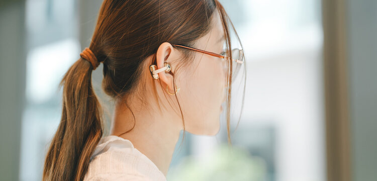Closeup business asian woman wear wireless earbuds listening digital content or mic using ai chatbot